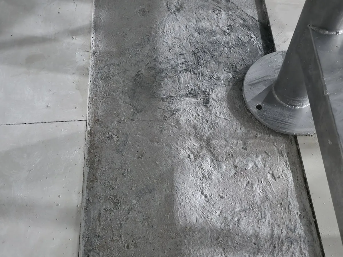 Base de concreto sendo preparada e tratada antes de receber o revestimento